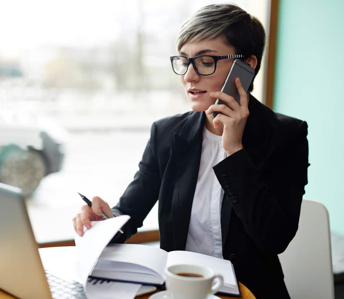 A broker working a package from a laptop and phone